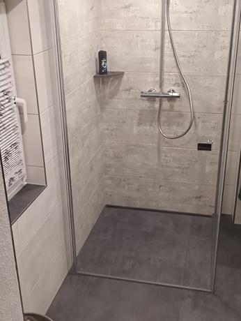 Helle Glas-Eckdusche mit Wandfliesen in grauer Betonoptik